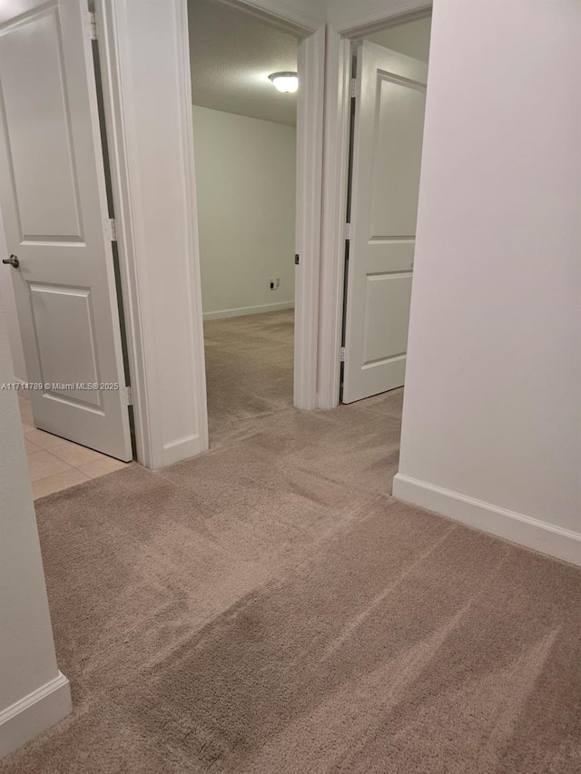 corridor with a textured ceiling and light colored carpet