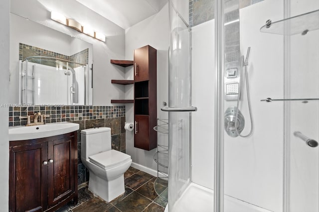 bathroom featuring decorative backsplash, toilet, a shower with shower door, and vanity