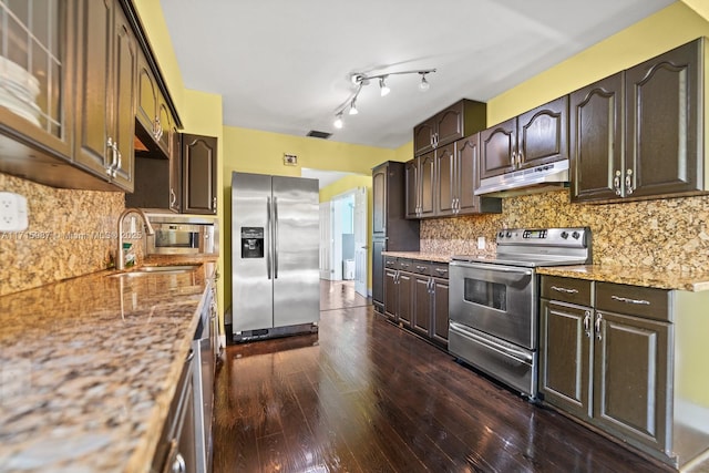 kitchen with light stone countertops, sink, stainless steel appliances, decorative backsplash, and dark brown cabinets