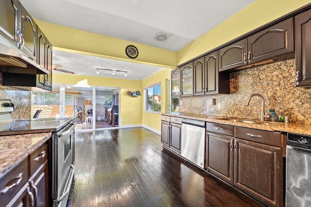 kitchen featuring decorative backsplash, appliances with stainless steel finishes, light stone countertops, dark brown cabinets, and sink