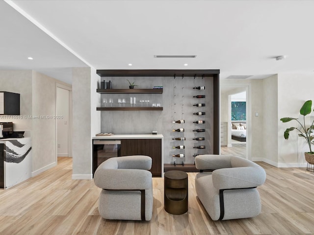 bar with light hardwood / wood-style flooring and beverage cooler