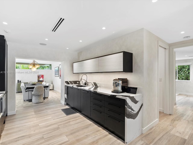 kitchen featuring light wood-type flooring, a notable chandelier, and sink