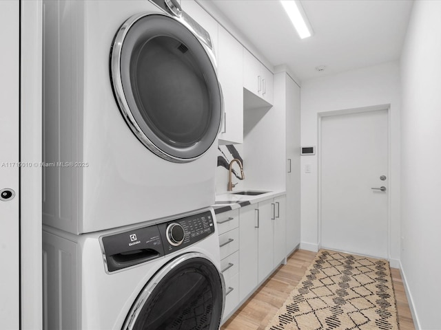 washroom featuring cabinets, stacked washing maching and dryer, light hardwood / wood-style flooring, and sink