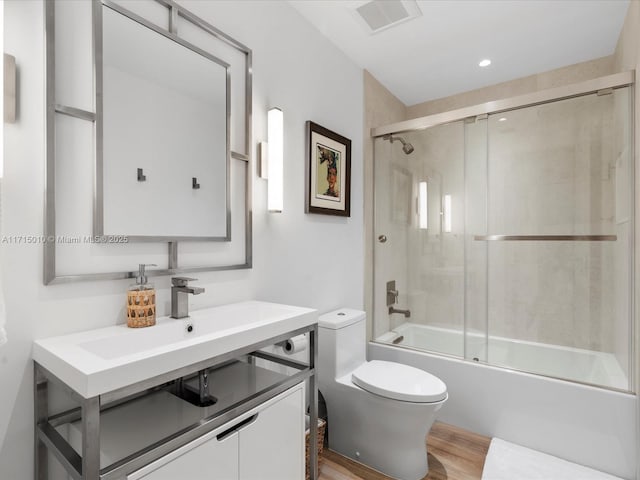 full bathroom featuring hardwood / wood-style floors, toilet, enclosed tub / shower combo, and sink