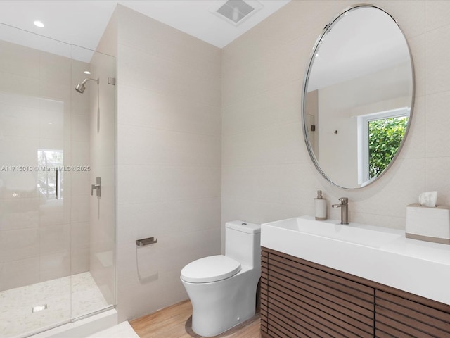 bathroom with vanity, hardwood / wood-style flooring, toilet, tile walls, and an enclosed shower