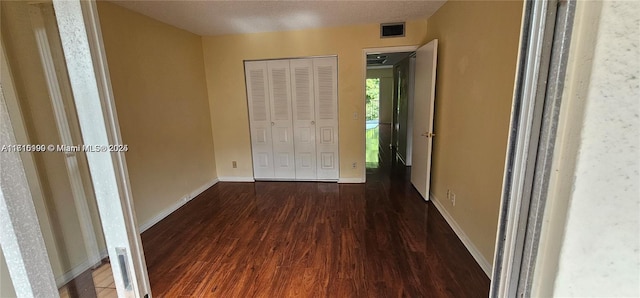 hallway with a textured ceiling and dark hardwood / wood-style floors