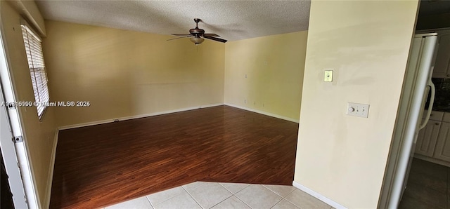 tiled empty room with ceiling fan and a textured ceiling