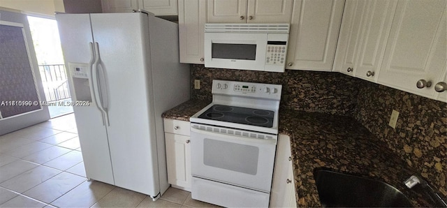 kitchen with decorative backsplash, dark stone counters, white appliances, light tile patterned floors, and white cabinets