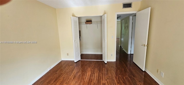 unfurnished bedroom with a closet and dark wood-type flooring