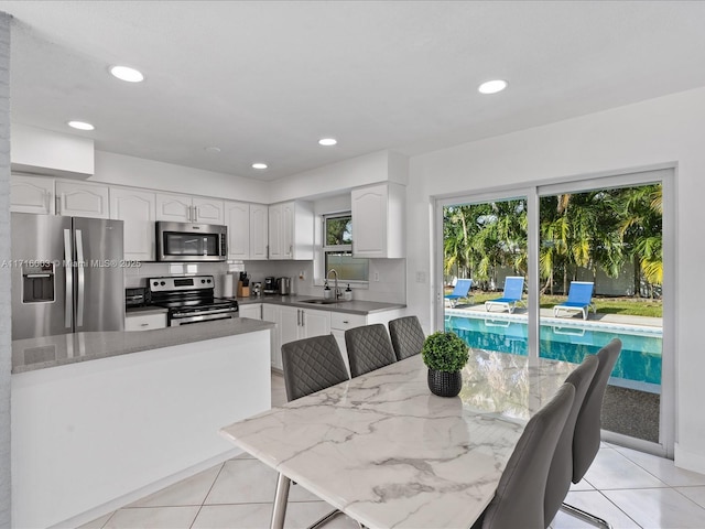 dining area featuring sink, light tile patterned floors, and plenty of natural light