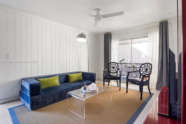 living room featuring tile patterned flooring, ceiling fan, and wooden walls