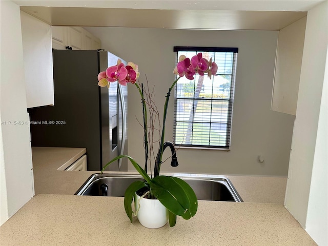 kitchen with stainless steel refrigerator with ice dispenser, plenty of natural light, sink, and white cabinets