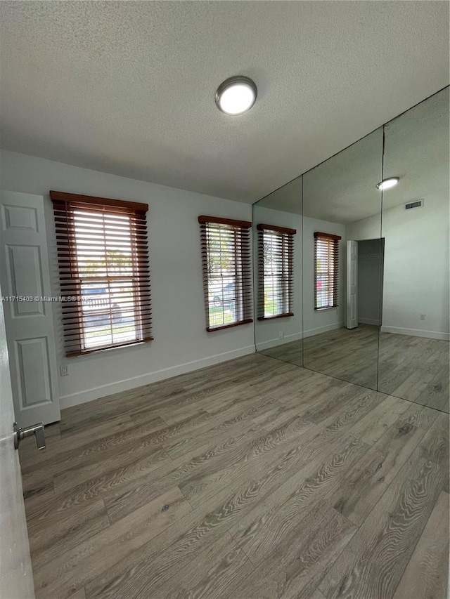 spare room with hardwood / wood-style floors and a textured ceiling