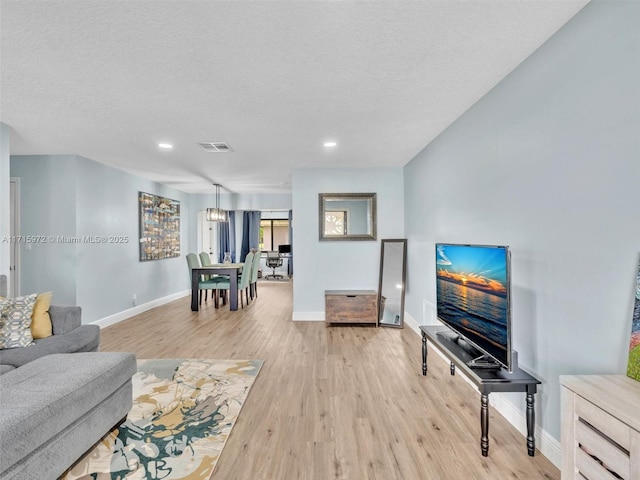 living room featuring light wood-type flooring and a textured ceiling