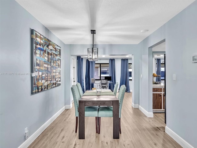 dining space featuring an inviting chandelier, a textured ceiling, and light hardwood / wood-style flooring