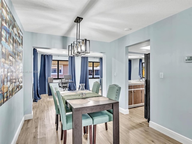 dining area with light wood-type flooring and an inviting chandelier