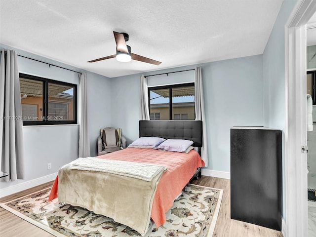 bedroom featuring ceiling fan, light hardwood / wood-style flooring, and a textured ceiling