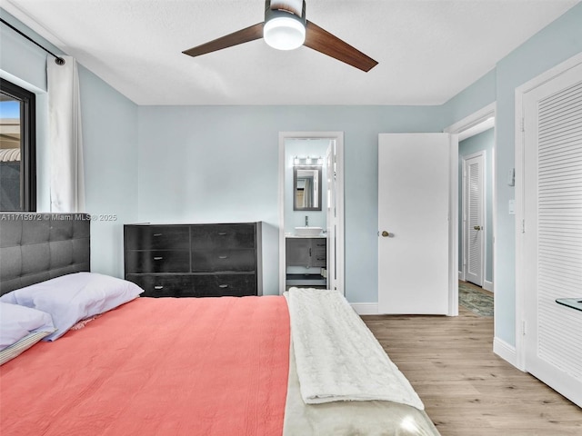 bedroom featuring ceiling fan, sink, light wood-type flooring, and ensuite bathroom