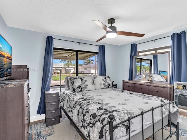 bedroom with ceiling fan, a textured ceiling, access to outside, and multiple windows