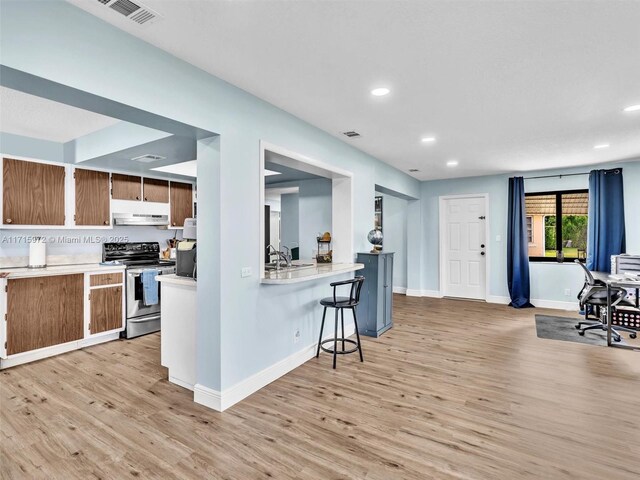 6708 NW 58th Ct, Tamarac, FL 33321 - kitchen with sink, light hardwood / wood-style flooring, kitchen peninsula, stainless steel electric range, and a breakfast bar