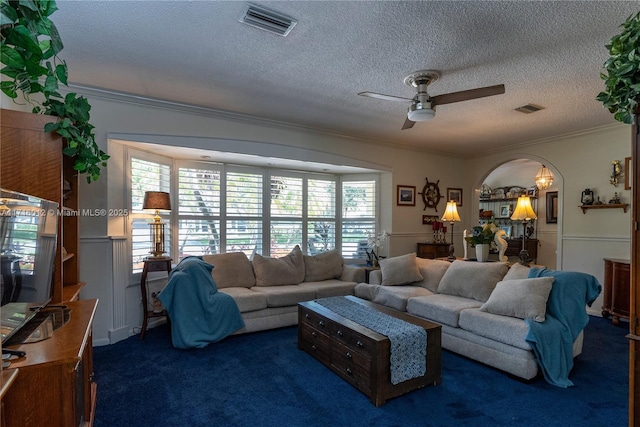 carpeted living room with ceiling fan, a textured ceiling, and ornamental molding