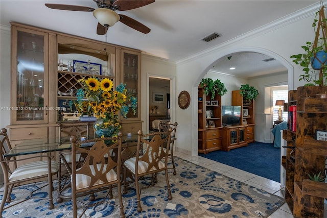 tiled dining space featuring ceiling fan and ornamental molding