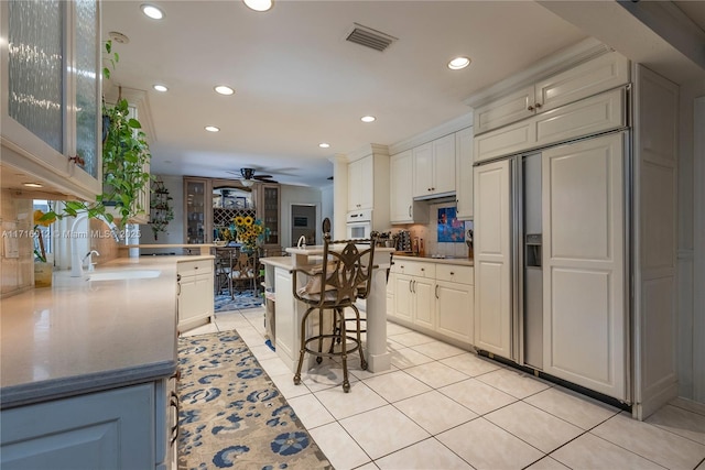 kitchen featuring white oven, ceiling fan, paneled built in refrigerator, kitchen peninsula, and a breakfast bar area