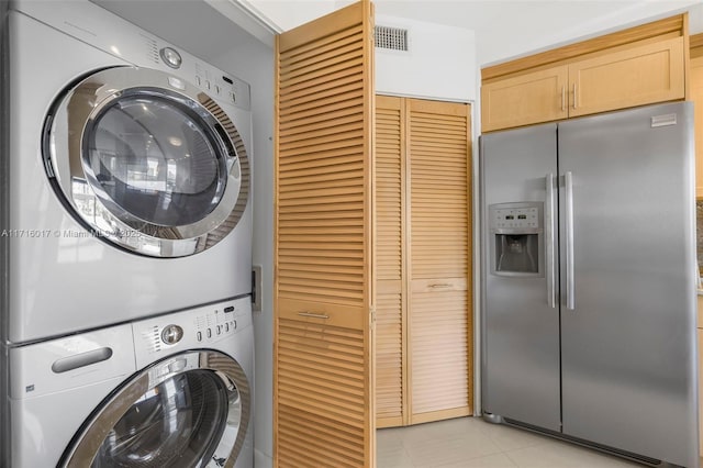 clothes washing area with stacked washer and dryer and light tile patterned floors