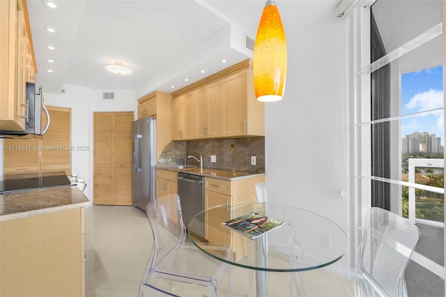 kitchen featuring sink, hanging light fixtures, decorative backsplash, light brown cabinetry, and appliances with stainless steel finishes