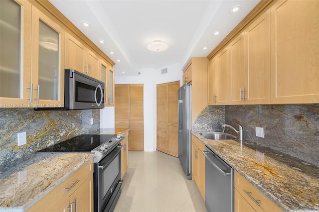 kitchen featuring appliances with stainless steel finishes, backsplash, stone countertops, and sink