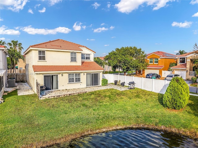 back of property with a water view, a yard, and central AC