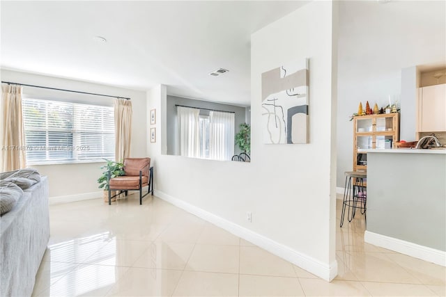 interior space featuring baseboards, visible vents, and light tile patterned floors