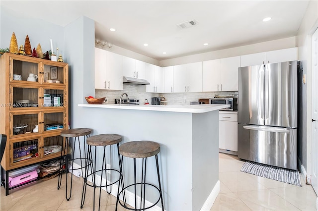 kitchen featuring a kitchen bar, kitchen peninsula, white cabinetry, and stainless steel appliances