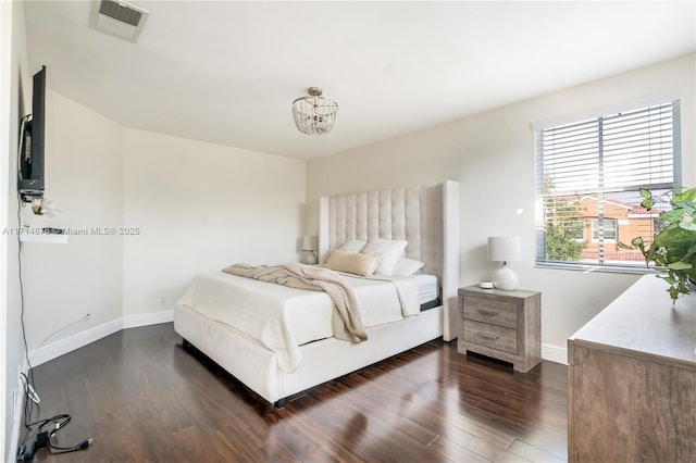 bedroom with a notable chandelier, visible vents, baseboards, and dark wood finished floors