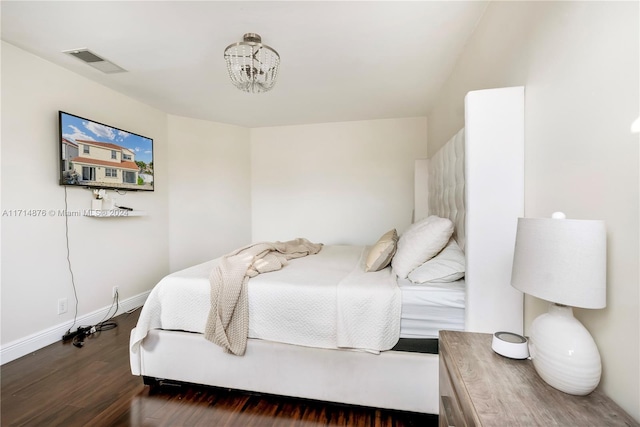 bedroom with a chandelier and dark hardwood / wood-style flooring