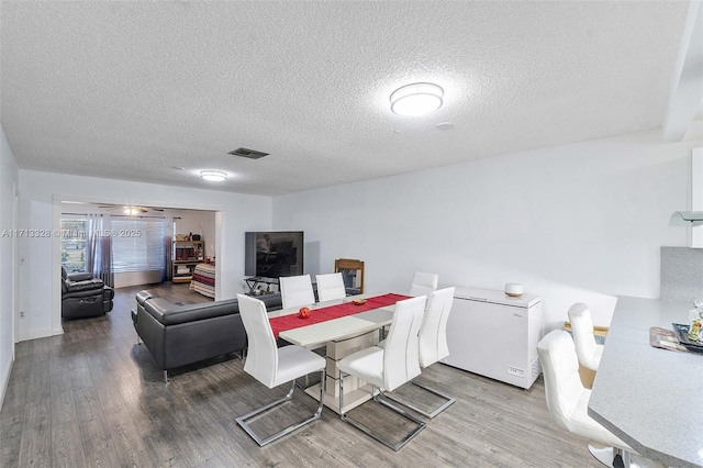 dining area featuring a textured ceiling and hardwood / wood-style flooring