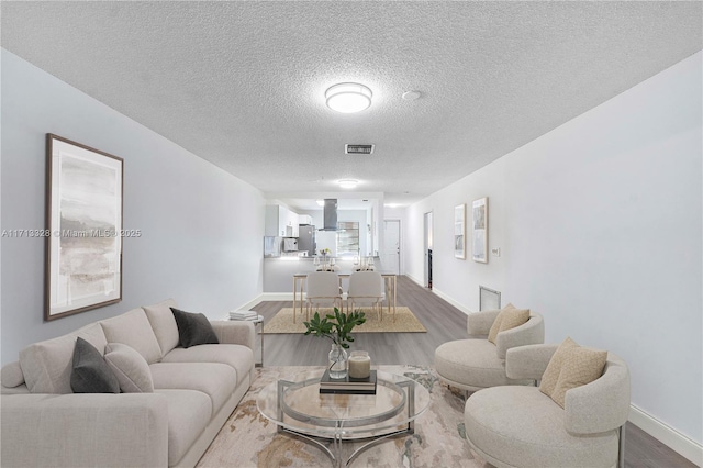 living room featuring visible vents, a textured ceiling, dark wood-type flooring, and baseboards