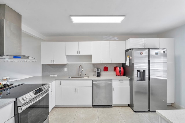 kitchen featuring a sink, wall chimney range hood, white cabinetry, appliances with stainless steel finishes, and light countertops