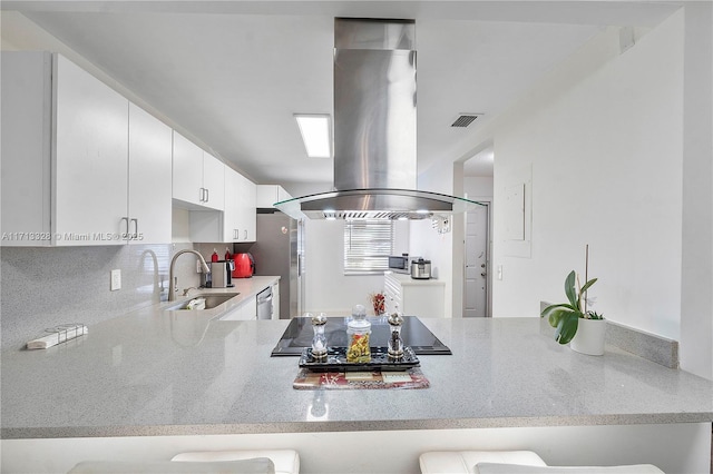 kitchen with visible vents, a peninsula, island exhaust hood, a sink, and appliances with stainless steel finishes