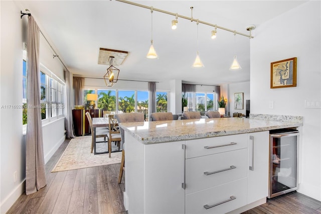 kitchen with a breakfast bar, dark wood-type flooring, white cabinets, wine cooler, and decorative light fixtures