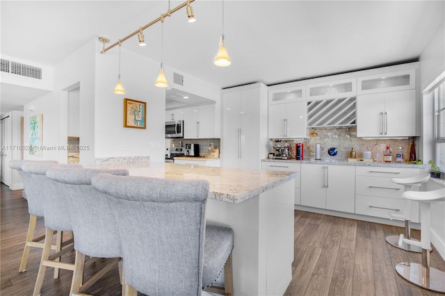 kitchen featuring a kitchen breakfast bar, backsplash, white cabinets, and stainless steel appliances