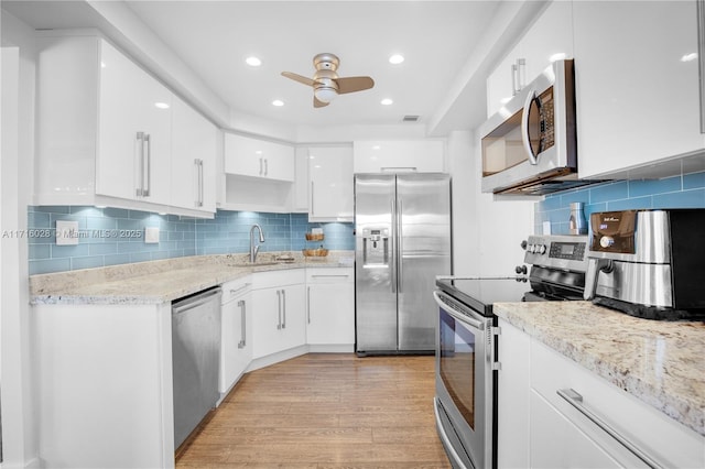 kitchen with white cabinets, appliances with stainless steel finishes, light hardwood / wood-style flooring, and ceiling fan