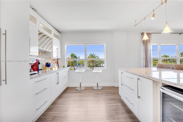 kitchen featuring hanging light fixtures, light stone countertops, tasteful backsplash, white cabinetry, and beverage cooler