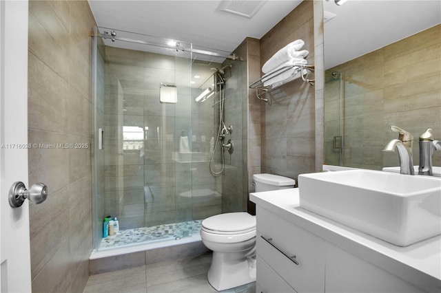 bathroom featuring an enclosed shower, vanity, tile walls, tile patterned flooring, and toilet