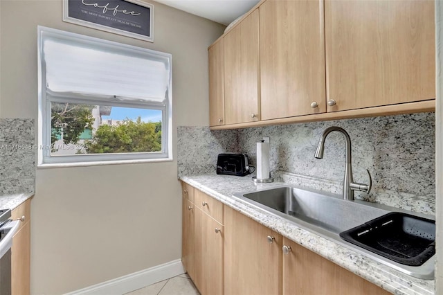 kitchen featuring light tile patterned floors, backsplash, light brown cabinetry, light stone countertops, and sink