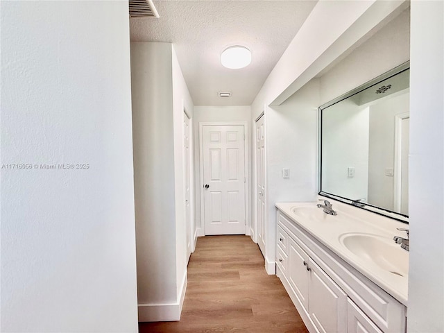 bathroom featuring vanity, wood-type flooring, and a textured ceiling