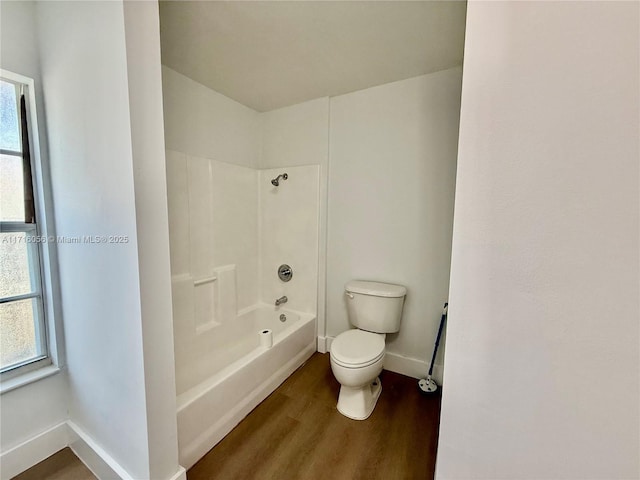 bathroom featuring shower / washtub combination, hardwood / wood-style floors, and toilet