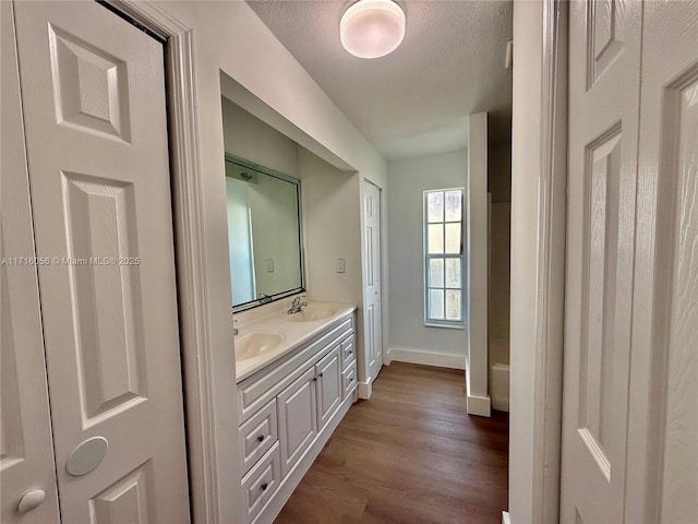 bathroom featuring a bath, vanity, wood-type flooring, and a textured ceiling