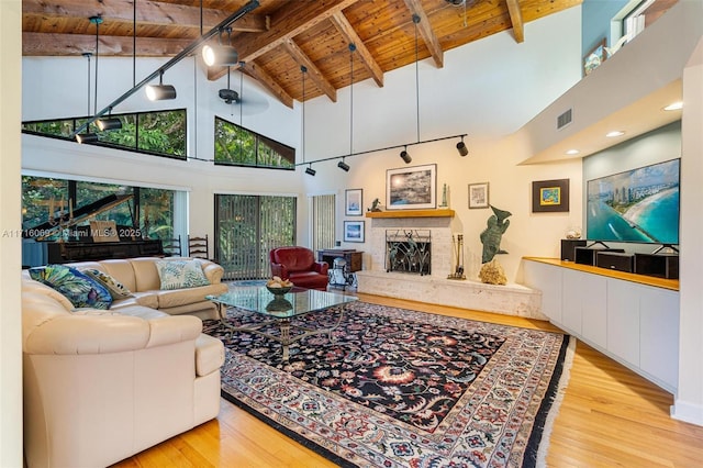 living room with a stone fireplace, beamed ceiling, wood ceiling, and high vaulted ceiling