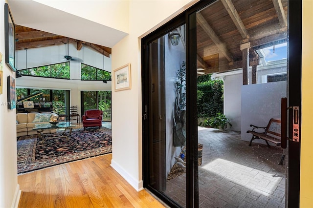 entryway with beamed ceiling, wood-type flooring, and high vaulted ceiling